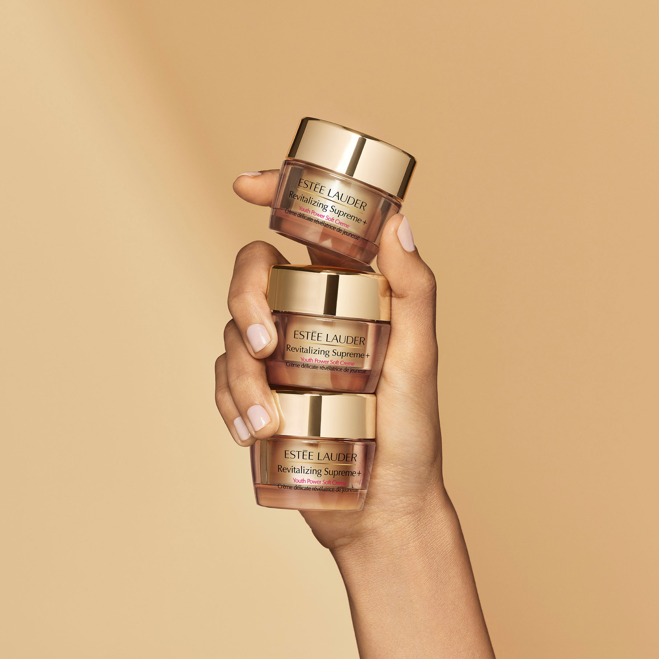 Hand holding three travel size cream containers
