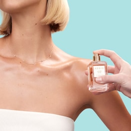 a female applying perfume to her décolletage 