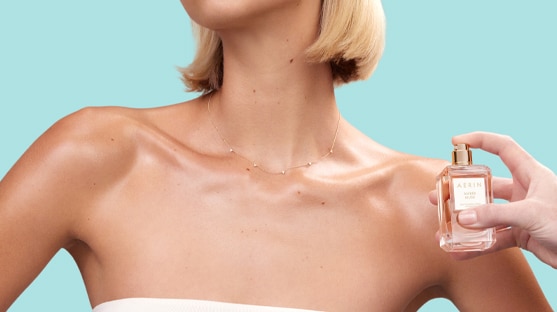 a female applying perfume to her décolletage 