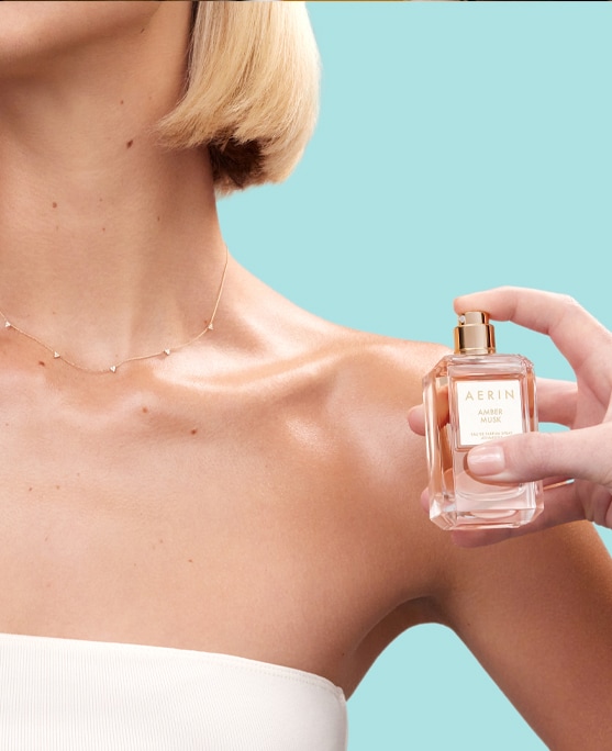 a female applying perfume to her décolletage 
